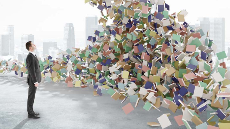 a business man standing in front of a wave of books.
