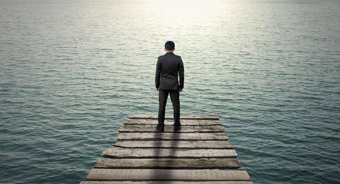 a business man standing at the end of a dock looking out at the water